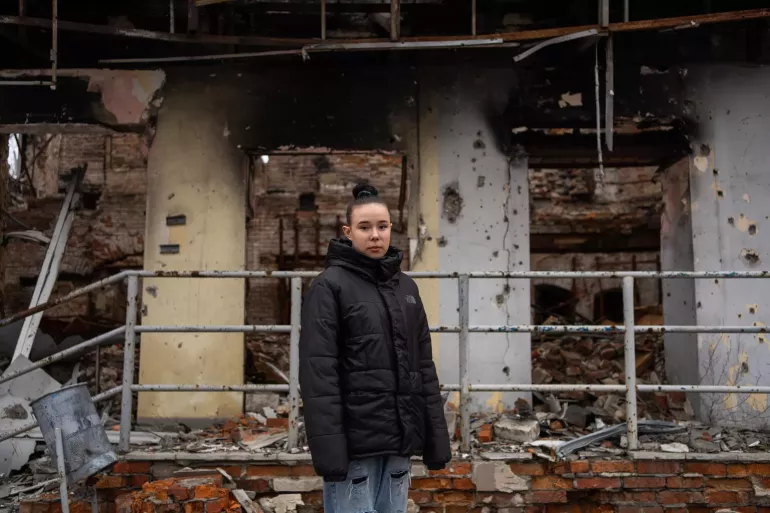 Izium, Kharkivska region, Ukraine. 15-year-old Nastia, who has survived a landmine explosion, is standing on the background of a building, pierced by gunshots and shelling.
