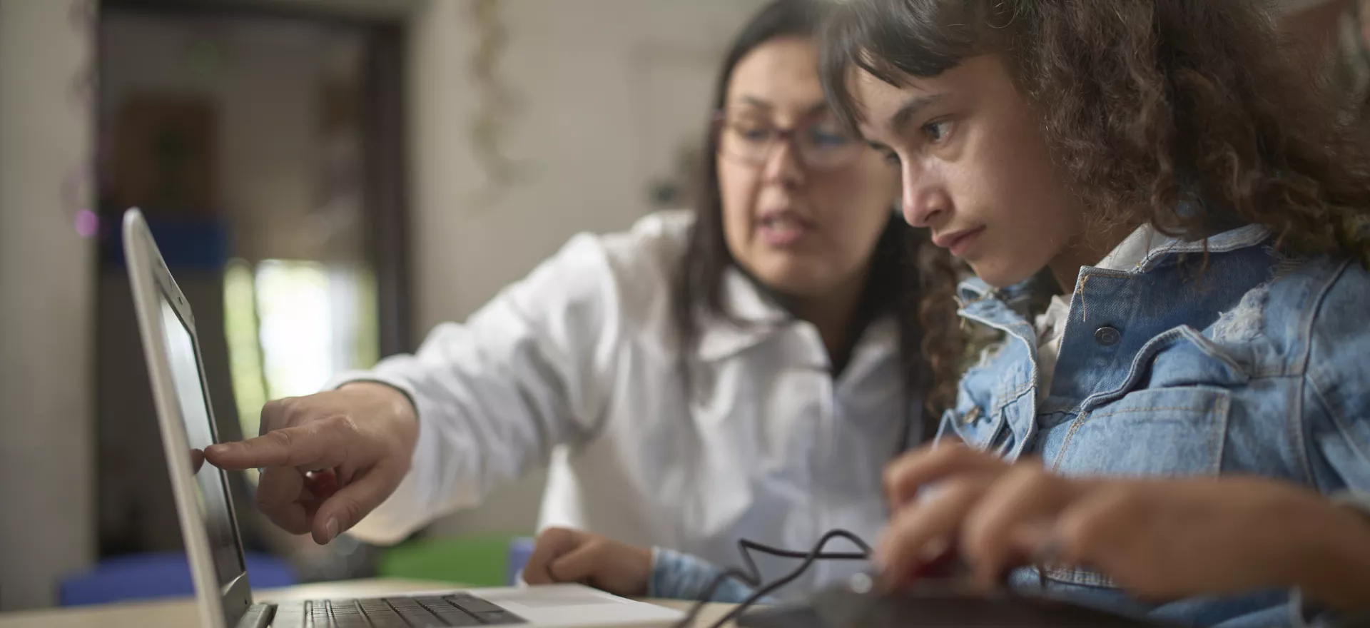 Una docente le da una explicaci&oacute;n a su alumna, una ni&ntilde;a con discapacidad, a trav&eacute;s de una computadora