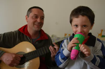 Un ni&ntilde;o canta con un micr&oacute;fono de pl&aacute;stico mientras su padre toca la guitarra