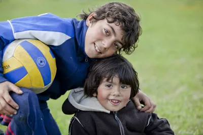 Dos ni&ntilde;os se abrazan, uno de ellos tiene una pelota en la mano.