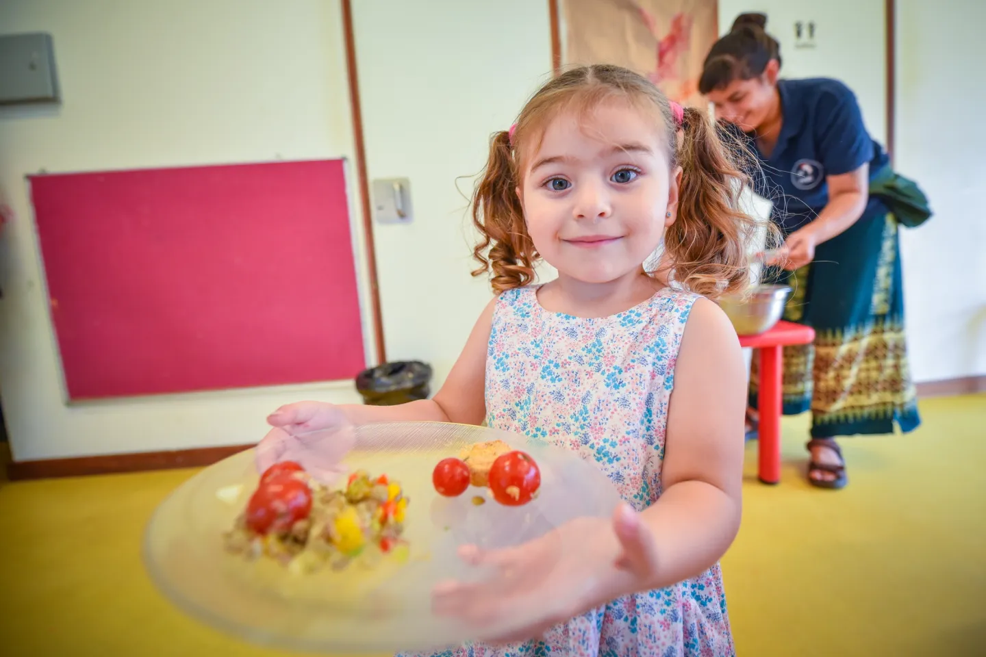 Ni&ntilde;a mostrando plato con croquetas y tomates cherry.