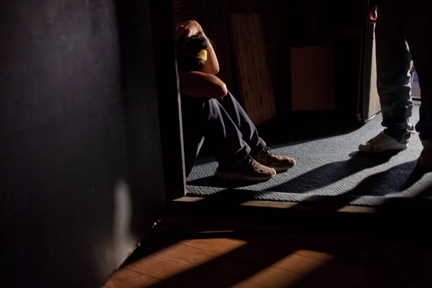 Un adolescente est&aacute; sentado en un rinc&oacute;n en un ambiente oscuro.
