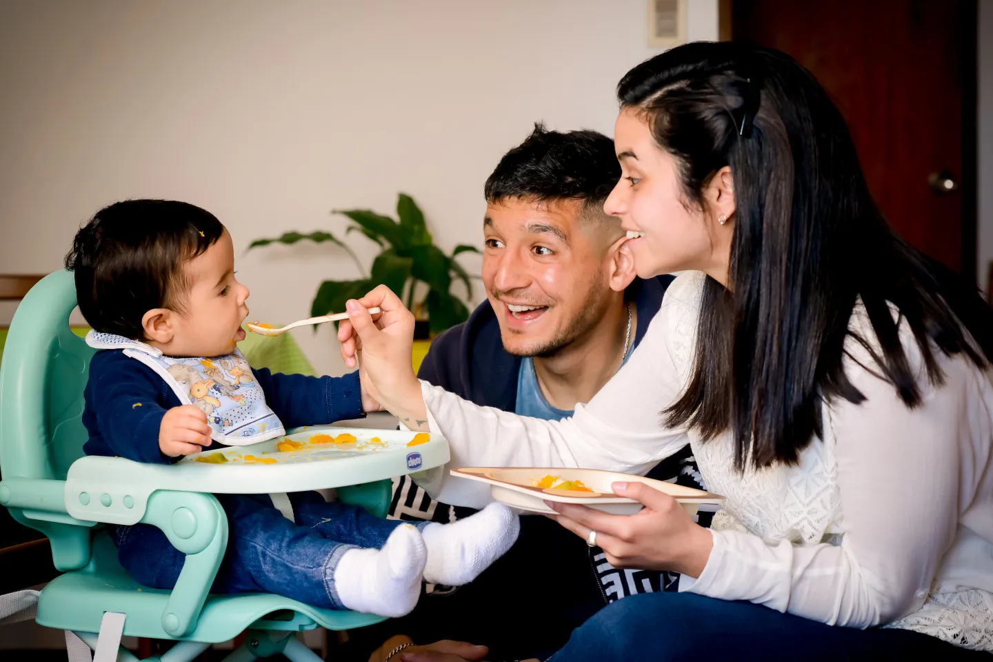 Madre y padre dando de comer pur&eacute; de calabaza a ni&ntilde;o de unos 6 meses aproximadamente.