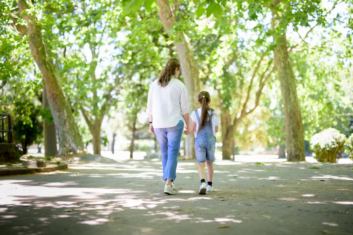 Madre y ni&ntilde;a caminando de la mano por una plaza