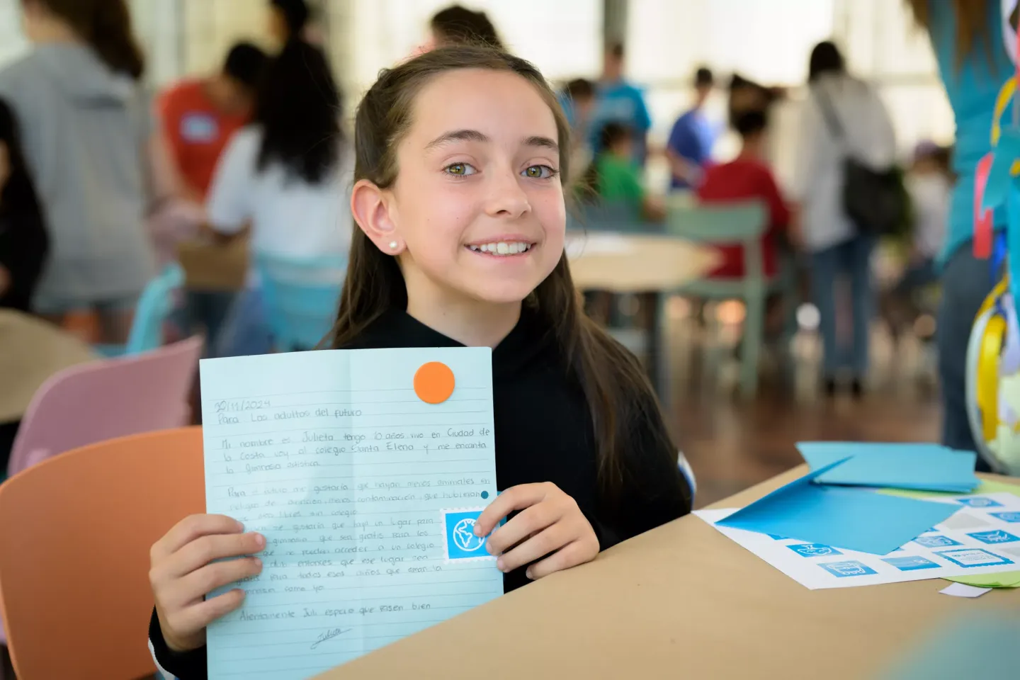 Ni&ntilde;a sonriendo con su carta al futuro en la mano