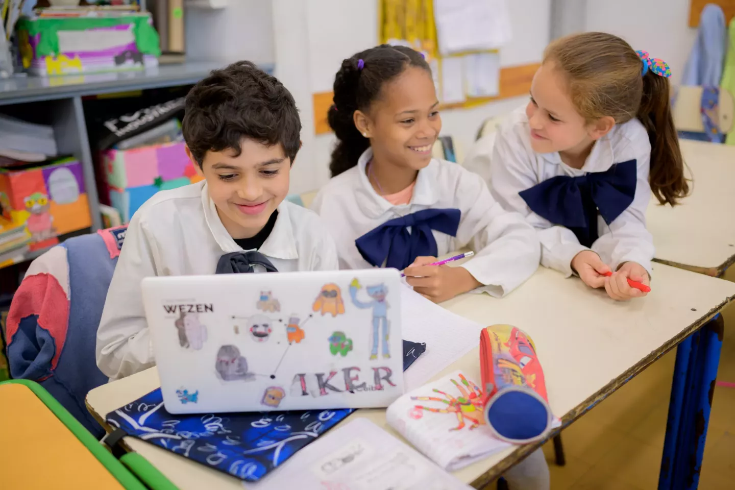 Un ni&ntilde;o y dos ni&ntilde;as sonriendo en el aula