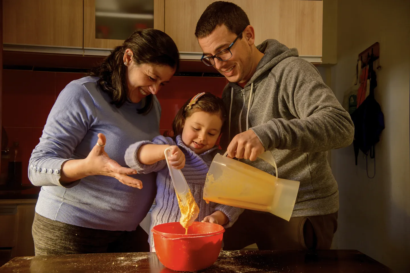 Hombre y mujer cocinando torta de naranja con ni&ntilde;a