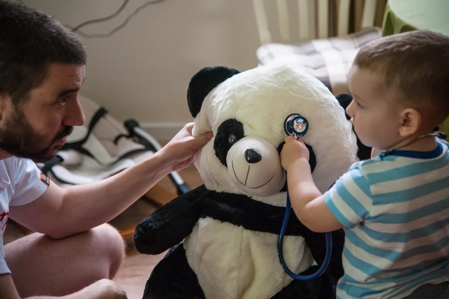 Padre y ni&ntilde;o juegan con un estetoscopio conun oso de peluche