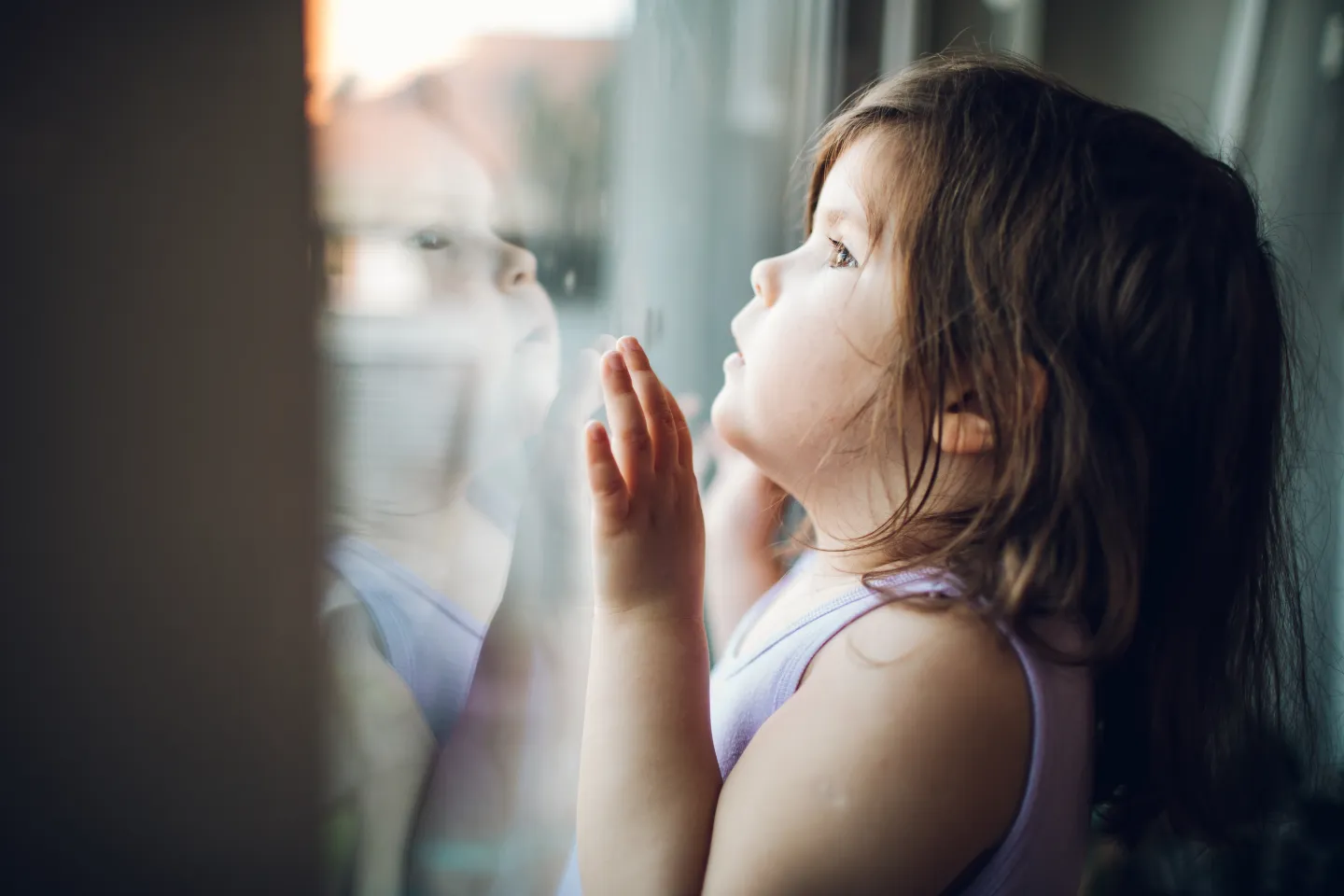 Ni&ntilde;a de unos 2 a&ntilde;os, mirando por la vantana hacia afuera.