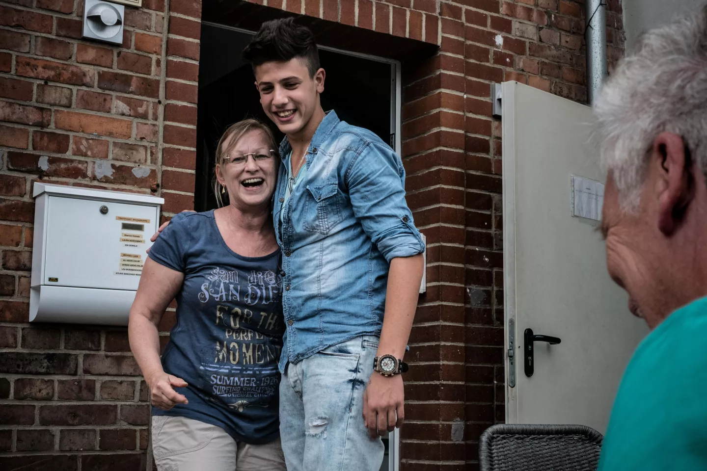 Joven abrazando a una mujer adulta en la puerta de su casa.