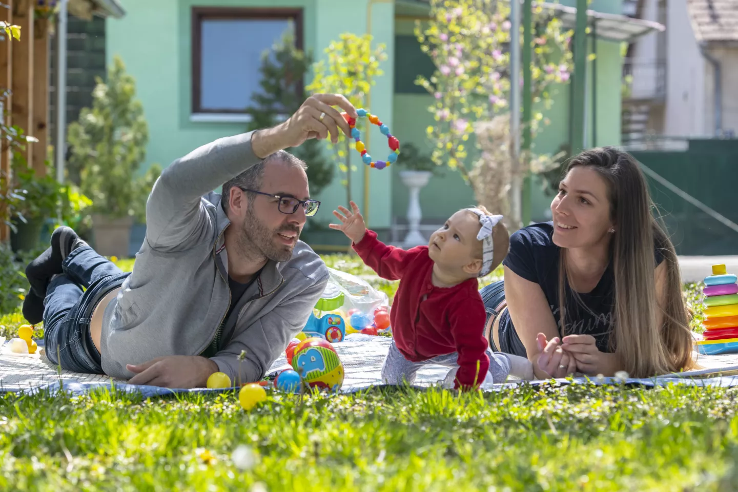 Padre y madre juegan con beb&eacute; sobre el pasto