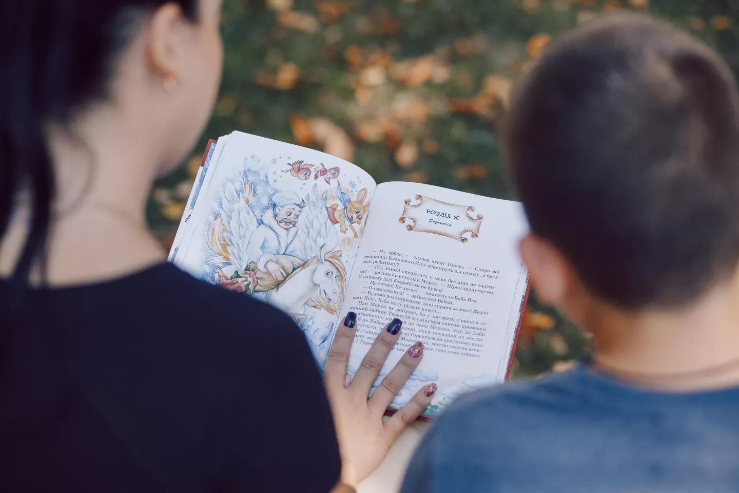 Madre y ni&ntilde;o, vistos de espaldas y de arriba, leyendo un libro.