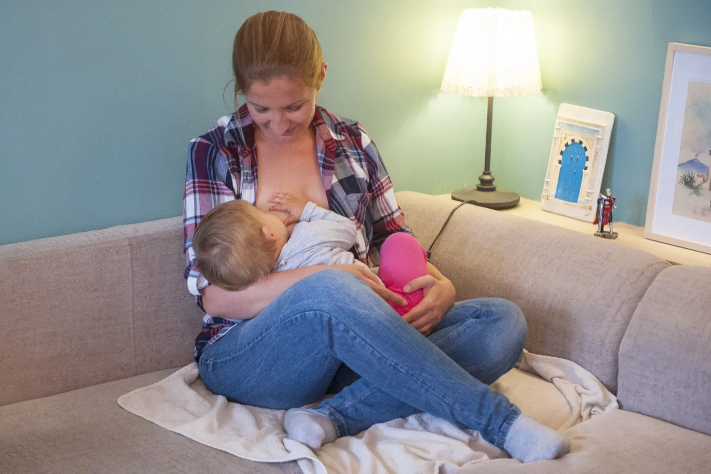 Mujer, sentada en sill&oacute;n, amamantando a ni&ntilde;a de un a&ntilde;o.