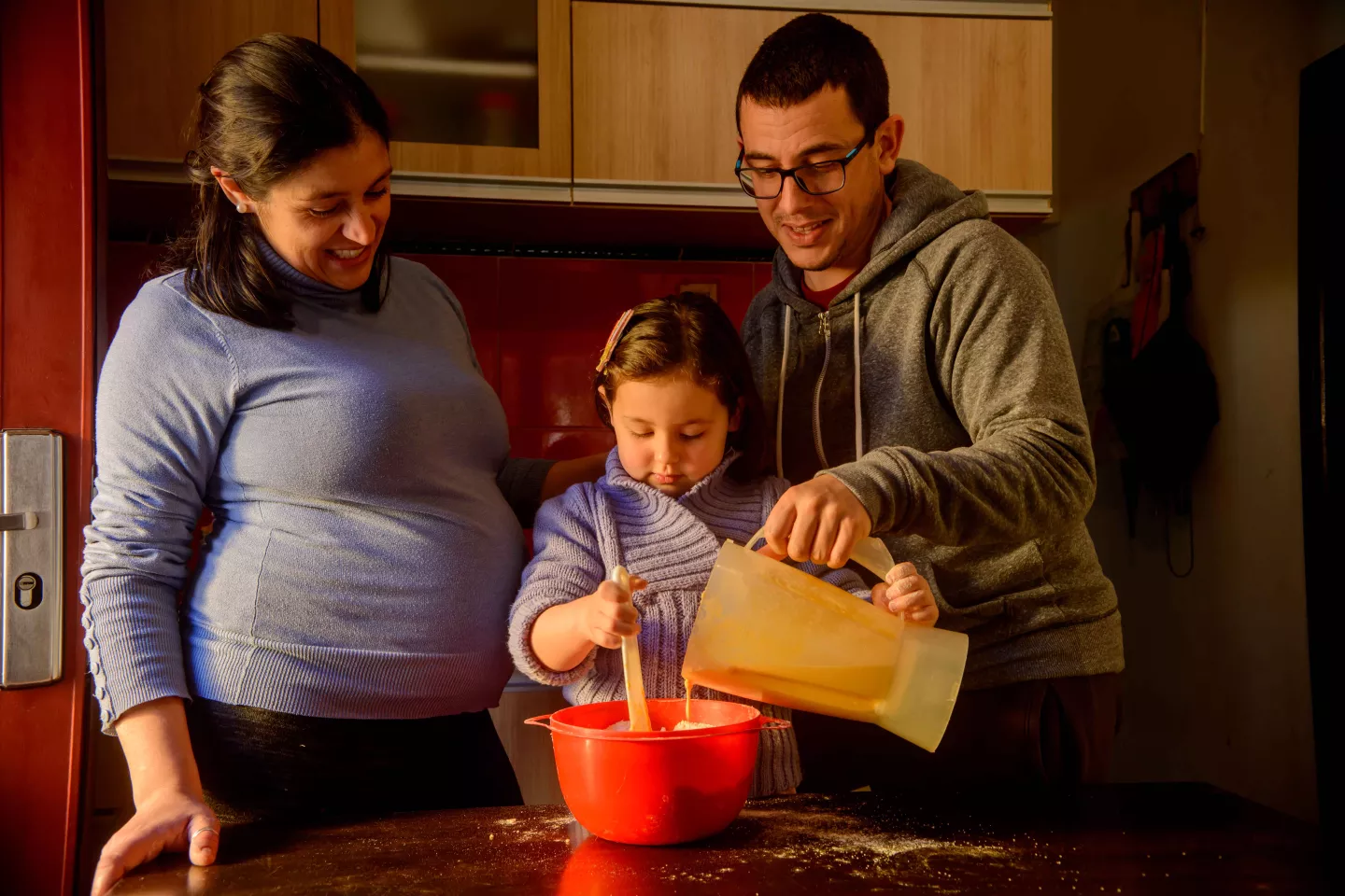 Madre embarazada y padre, cocinando con ni&ntilde;a de 4 a&ntilde;os