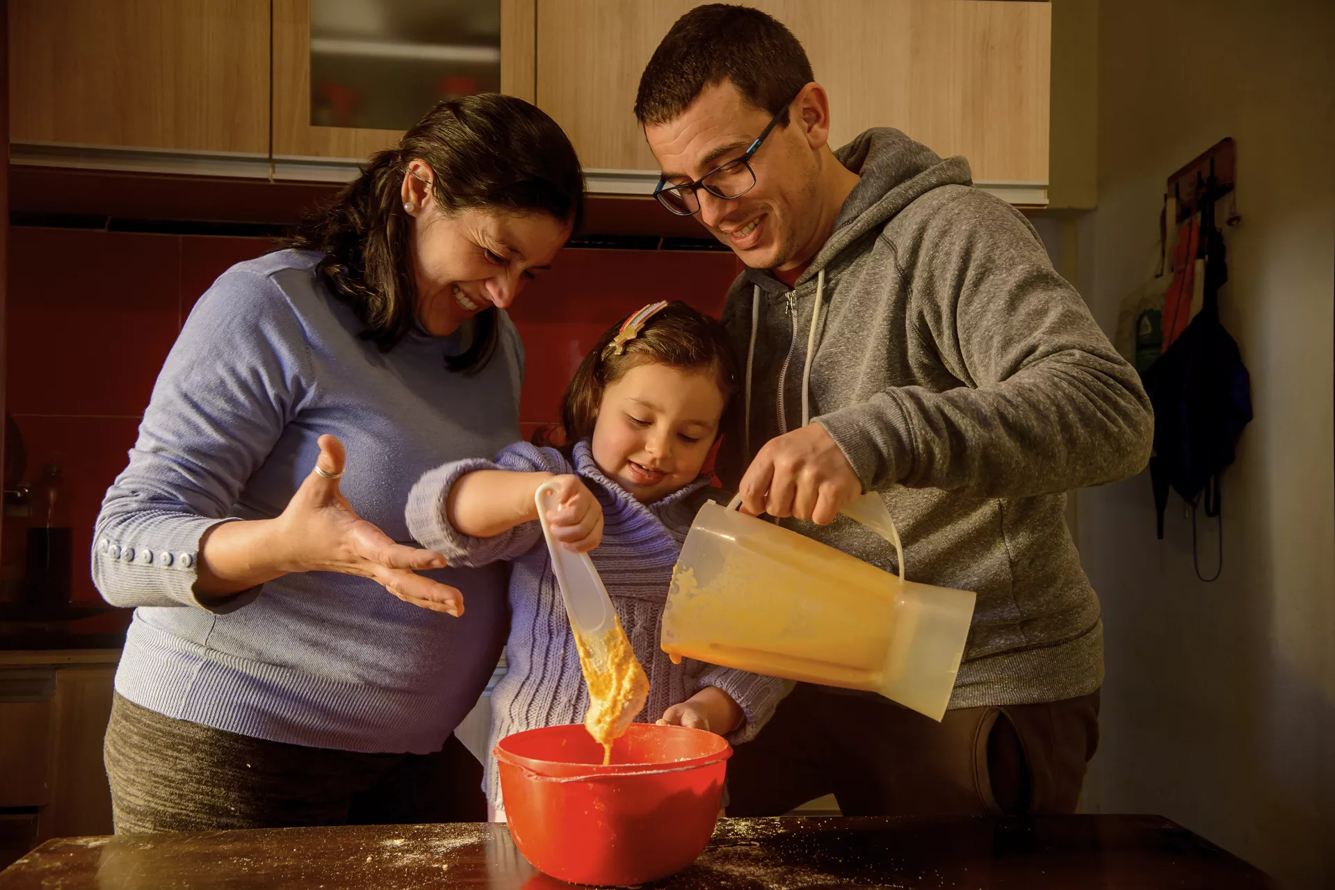 Hombre y mujer cocinando torta de naranja con ni&ntilde;a