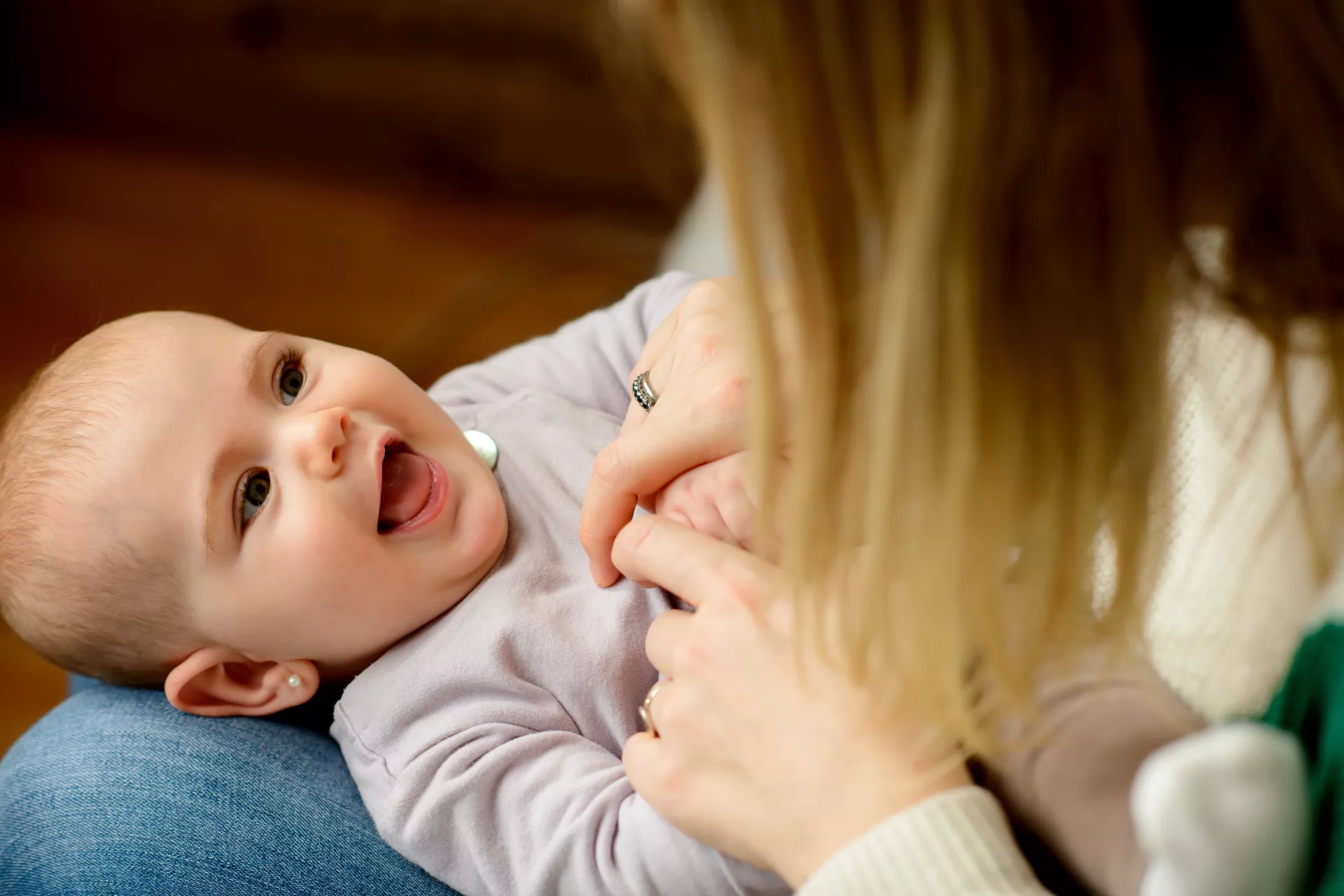 Beb&eacute; acostada en la falda de una mujer, mir&aacute;ndola a los ojos, mientras la mujer le hace cosquillas en el pecho.