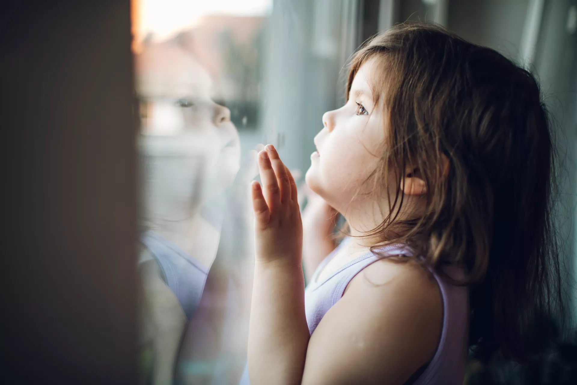 Ni&ntilde;a de unos 2 a&ntilde;os, mirando por la vantana hacia afuera.