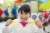 Una niña sonríe a cámara y sostiene unos hilos de colores