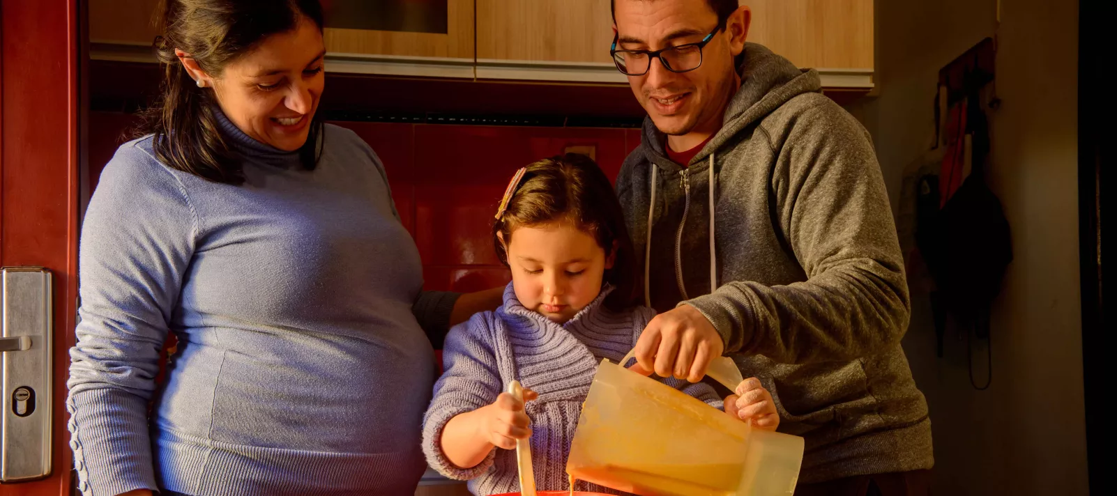 Madre embarazada y padre, cocinando con ni&ntilde;a de 4 a&ntilde;os