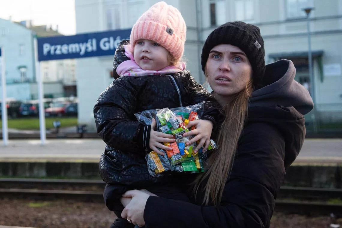 Mujer con ni&ntilde;a e brazos, en un Punto azul en una estaci&oacute;n de tren de Polonia