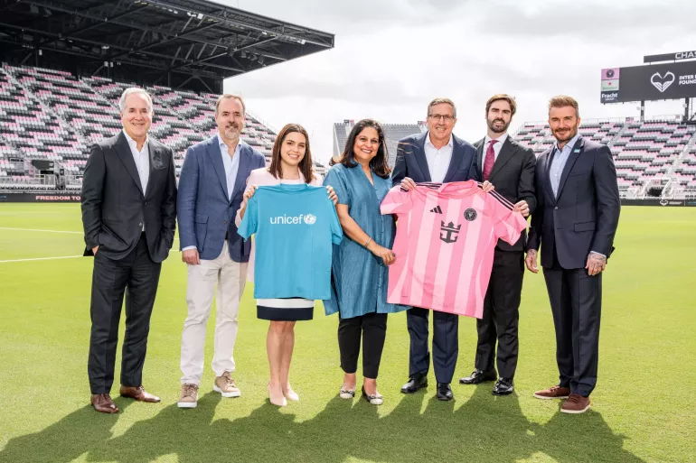 7 personas paradas en el campo de juego con las remeras de UNICEF y del Inter Miami CF