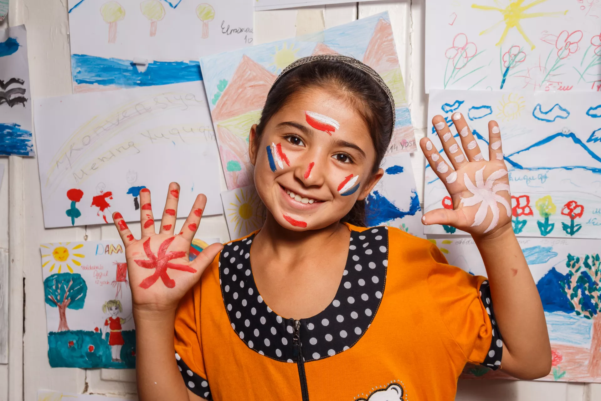 girl showing all 10 fingers on her hands covered in paint on camera