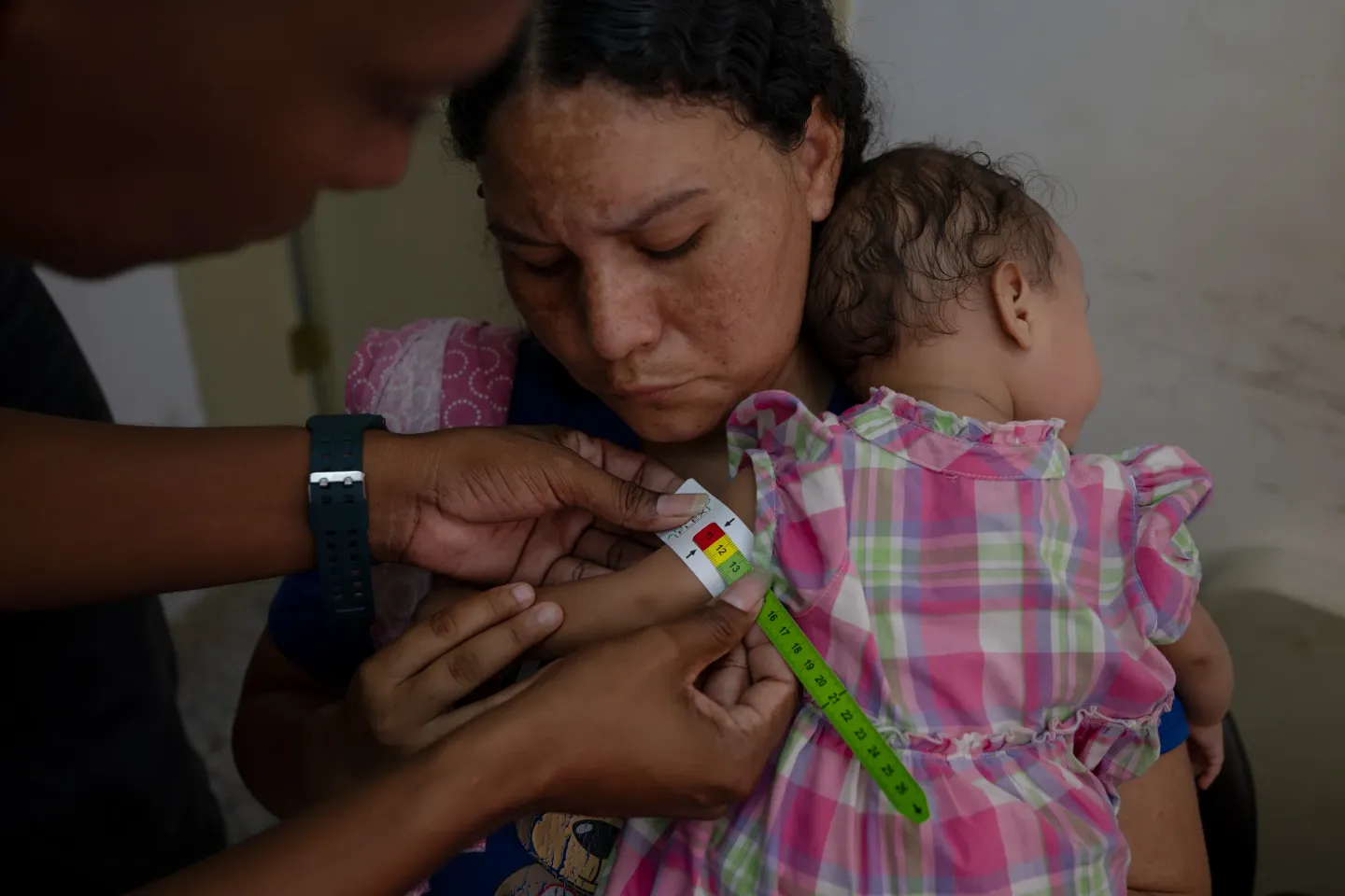 A health worker measures the mid-upper arm circumference of Anderbis Acosta&rsquo;s nine-month-old daughter, who was diagnosed with severe acute malnutrition, as her mother holds her during a UNICEF-supported health outreach session in Santa Luc&iacute;a del Tuy, Miranda State, Venezuela.