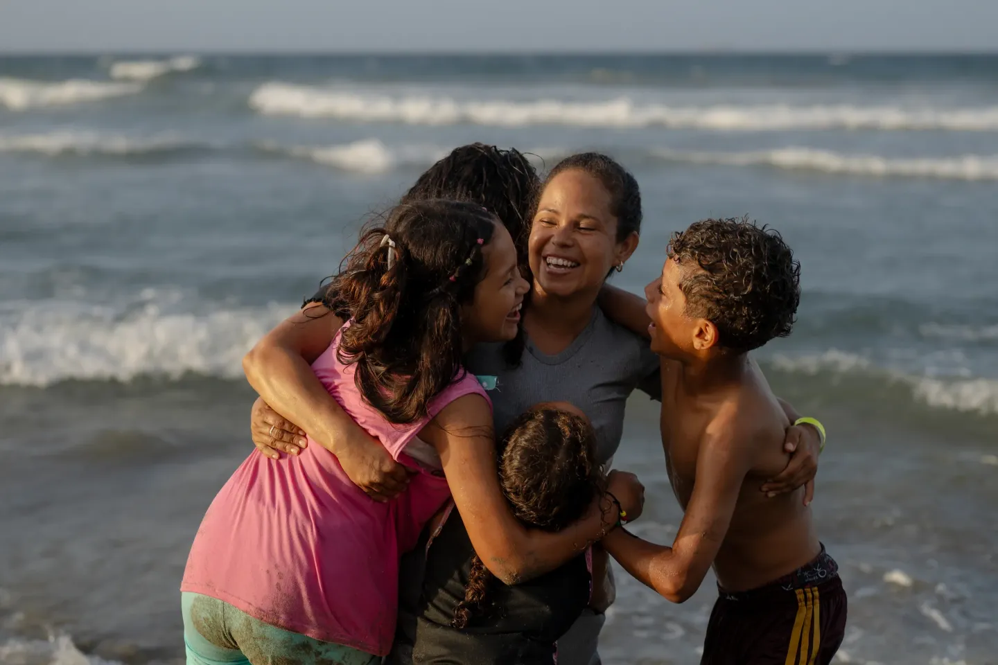 Dami&aacute;n, de 13 a&ntilde;os, su t&iacute;a Mercedes y su familia comparten un abrazo a orillas del mar en La Guaira, Venezuela.