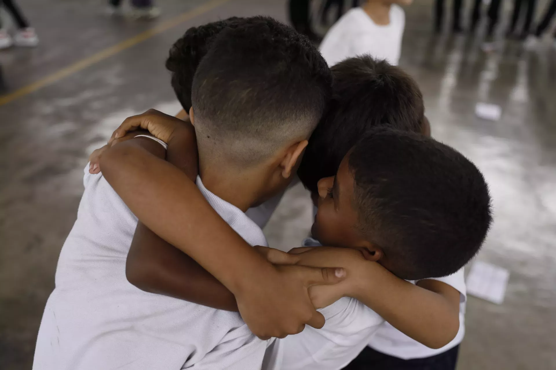 Ni&ntilde;os con uniforme escolar se abrazan entre ellos en el patio de su escuela