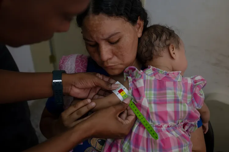 A health worker measures the mid-upper arm circumference of Anderbis Acosta&rsquo;s nine-month-old daughter, who was diagnosed with severe acute malnutrition, as her mother holds her during a UNICEF-supported health outreach session in Santa Luc&iacute;a del Tuy, Miranda State, Venezuela.