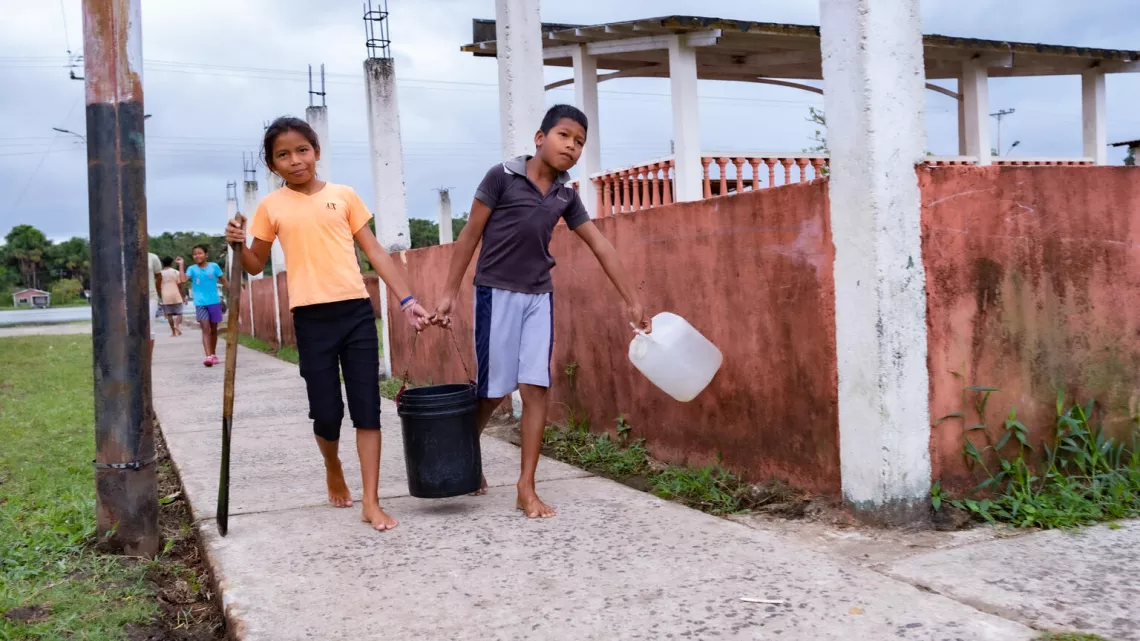 Dahir Franco, de 10 a&ntilde;os de edad, y su hermana se llevan a casa agua potable que recogieron en la planta de tratamiento de agua solar instalada por UNICEF en San Francisco de Guayo, en el estado de Delta Amacuro, el 21 de marzo de 2023.