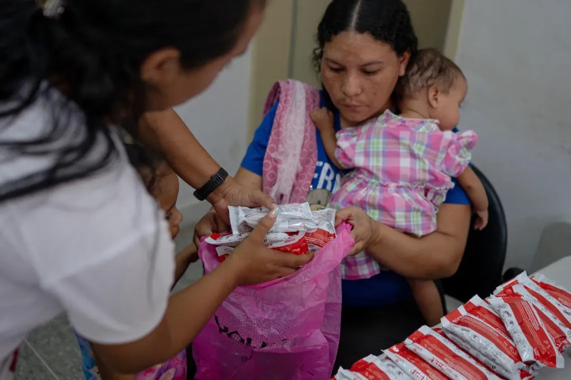 A health worker provides nutrition supplies to Anderbis Acosta as she holds her nine-month-old daughter during a UNICEF-supported health outreach session in Santa Luc&iacute;a del Tuy, Miranda State, Venezuela.