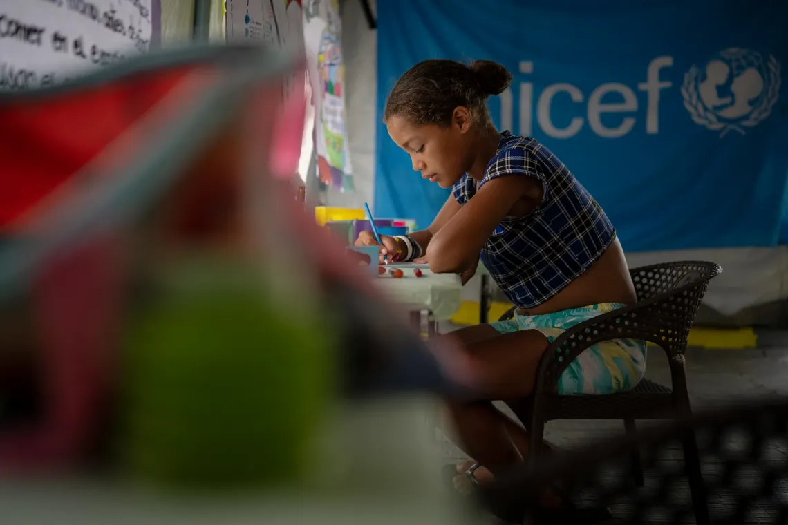 Naibelis, 12, writes a letter about her wishes for the future in a UNICEF-supported child-friendly space at the C&eacute;sar Nieves stadium transit camp.