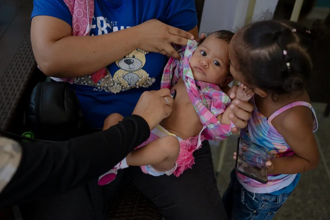 A health worker examines Anderbis Acosta&rsquo;s nine-month-old daughter as her mother holds her during a UNICEF-supported health outreach session in Santa Luc&iacute;a del Tuy, Miranda State, Venezuela.