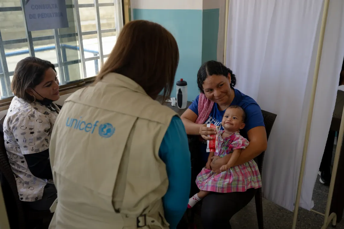Zulay Gonz&aacute;lez, UNICEF Venezuela Nutrition Officer, with Anderbis Acosta and her daughter during a health outreach session in Santa Luc&iacute;a de Tuy, Venezuela, on 16 September 2026. The baby receives ready-to-use therapeutic food (RUTF) after being diagnosed with acute malnutrition.