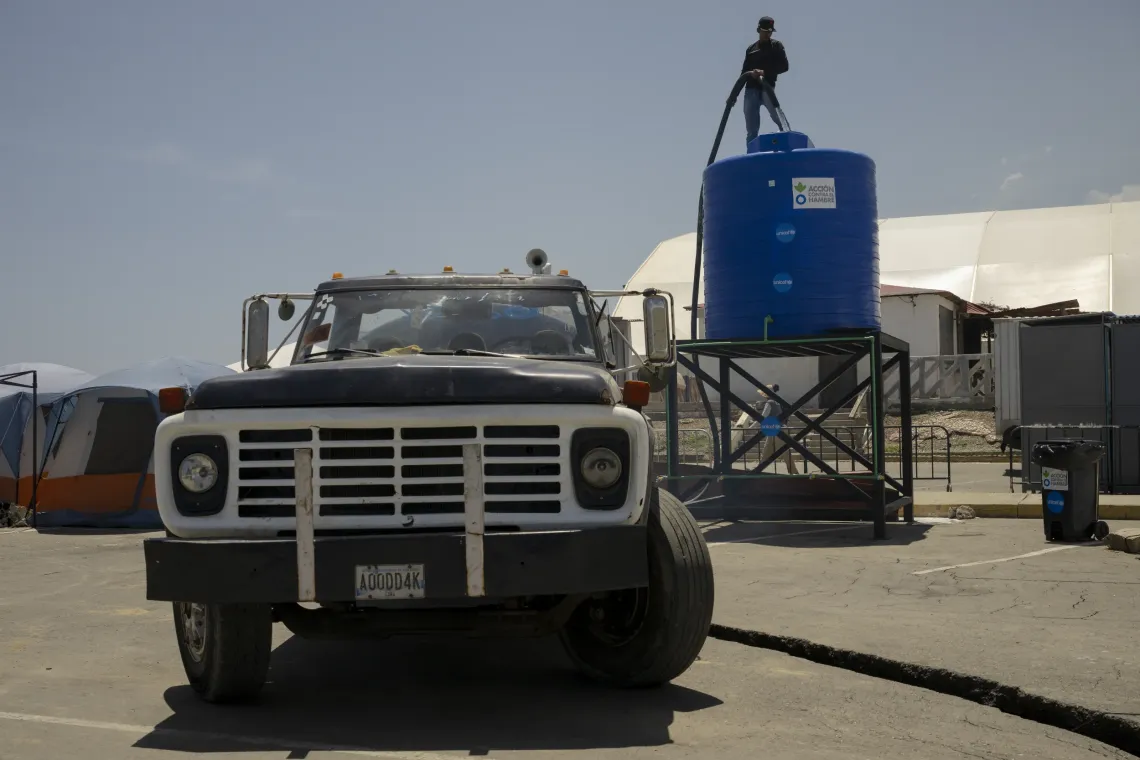 Un trabajador llena un tanque de almacenamiento de agua apoyado por UNICEF en el campamento temporal de Mare Abajo.