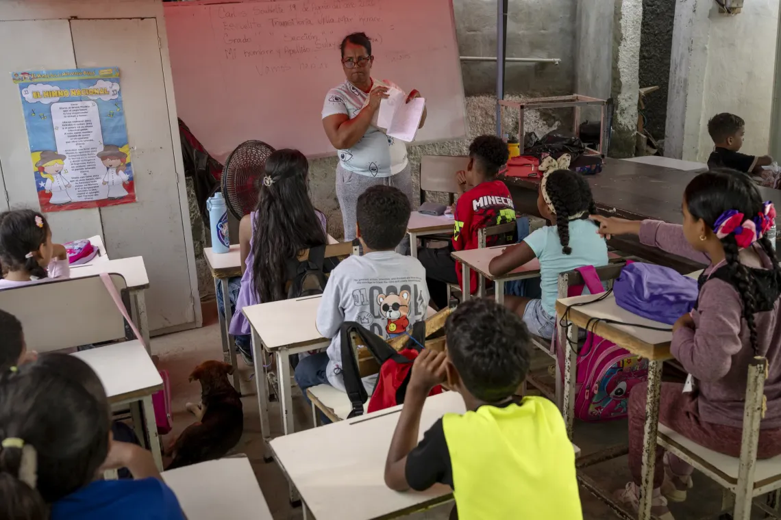 Una docente imparte una clase en una escuela temporal instalada en medio de una calle.