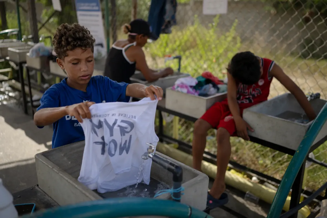 Dami&aacute;n, 13, washes a T-shirt at the communal laundry sinks in the temporary camp at the Jos&eacute; Mar&iacute;a Vargas sports complex in La Guaira.