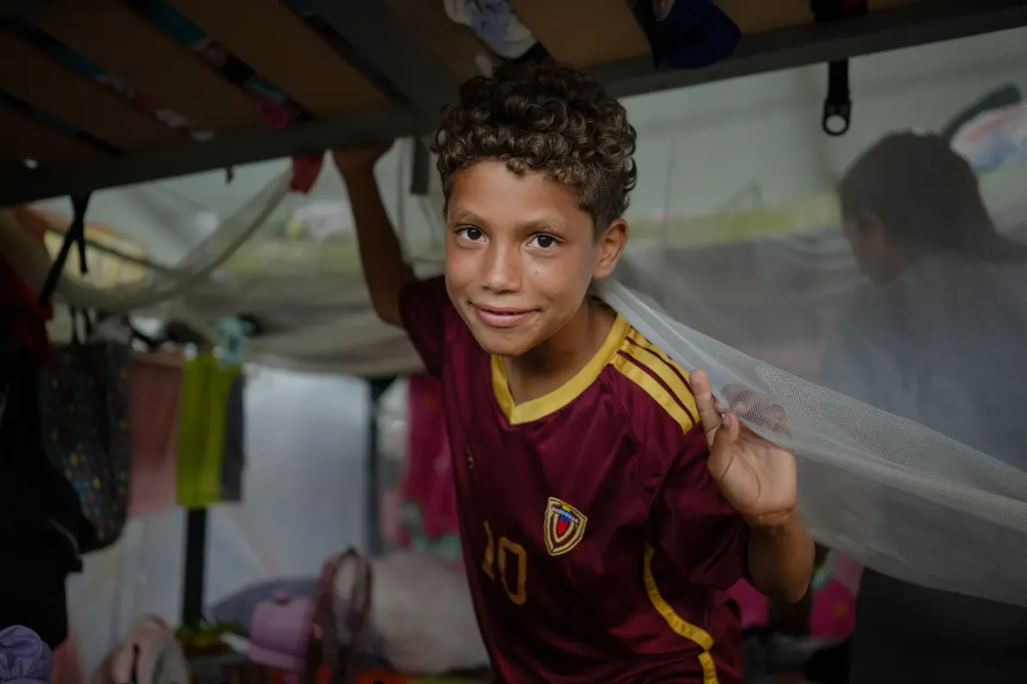 Dami&aacute;n, 13, beside his bunk bed at the temporary camp in the Jos&eacute; Mar&iacute;a Vargas sports complex in La Guaira, where he lives with his aunt Mercedes and their family.