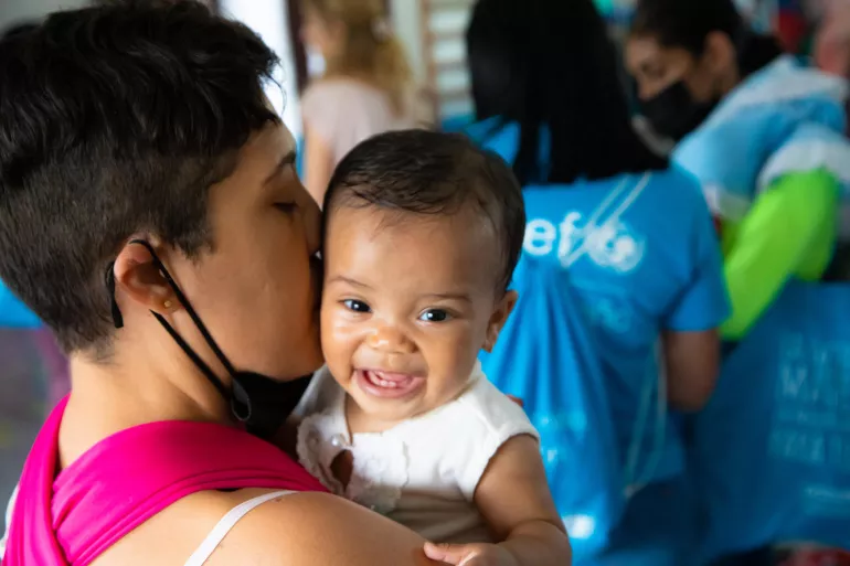 A mother holding her baby in her arms as she takes part in an activity at a UNICEF-supported health center.
