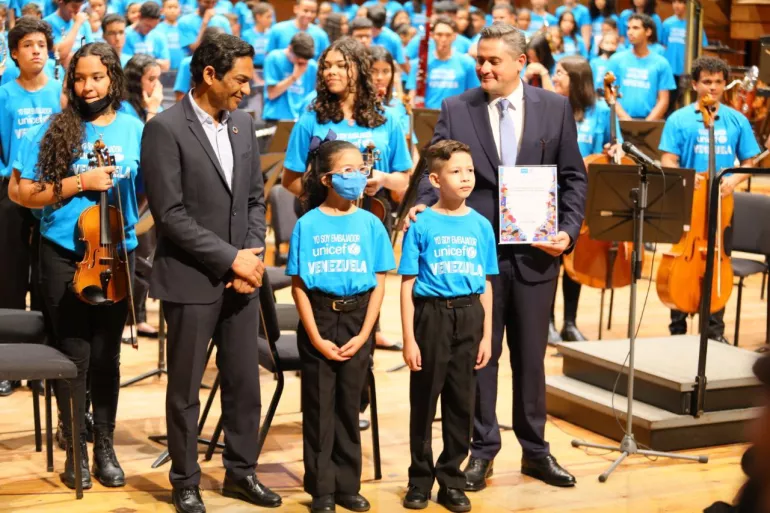 una ni&ntilde;a y un ni&ntilde;o acompa&ntilde;an al Representante de UNICEF y al Director de Fundamusical en el escenario del Centro de Acci&oacute;n Social por la M&uacute;sica en Caracas, en el marco del concierto de ratificaci&oacute;n de El Sistema como Embajador de Buena Voluntad