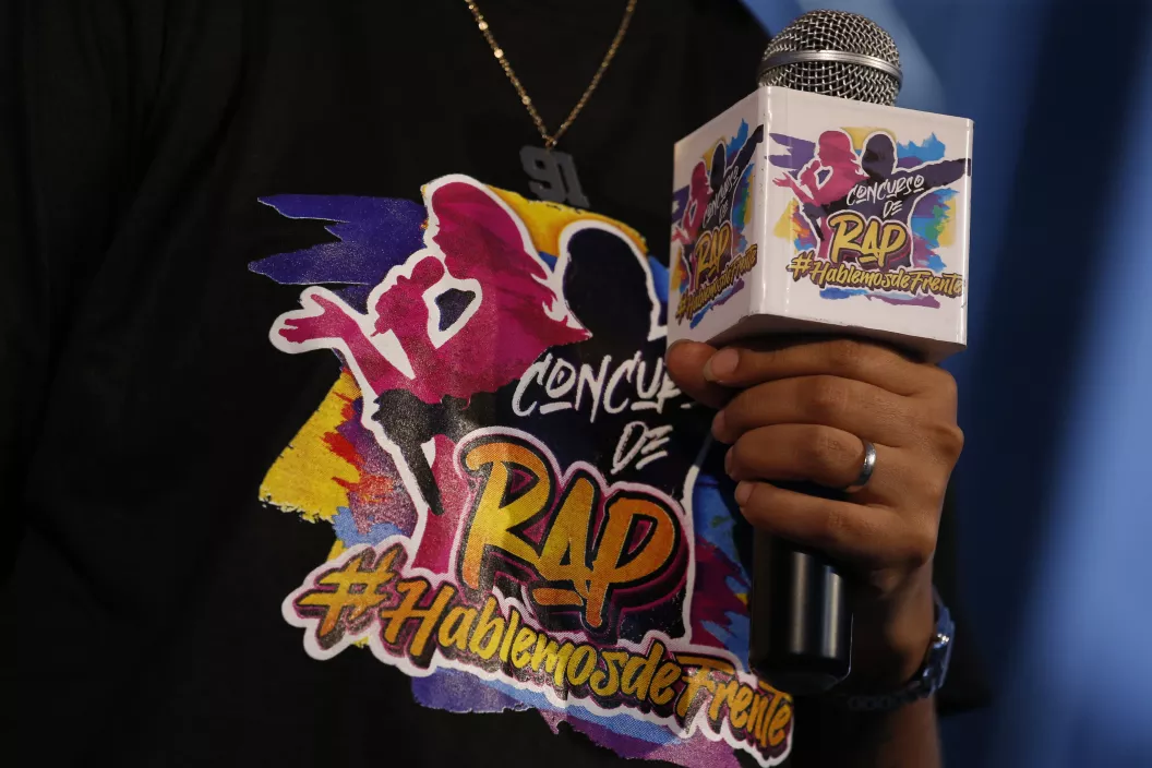 animador del evento de premiaci&oacute;n del concurso de rap Hablemos de frente sostiene micr&oacute;fono mostrando el logotema del concurso