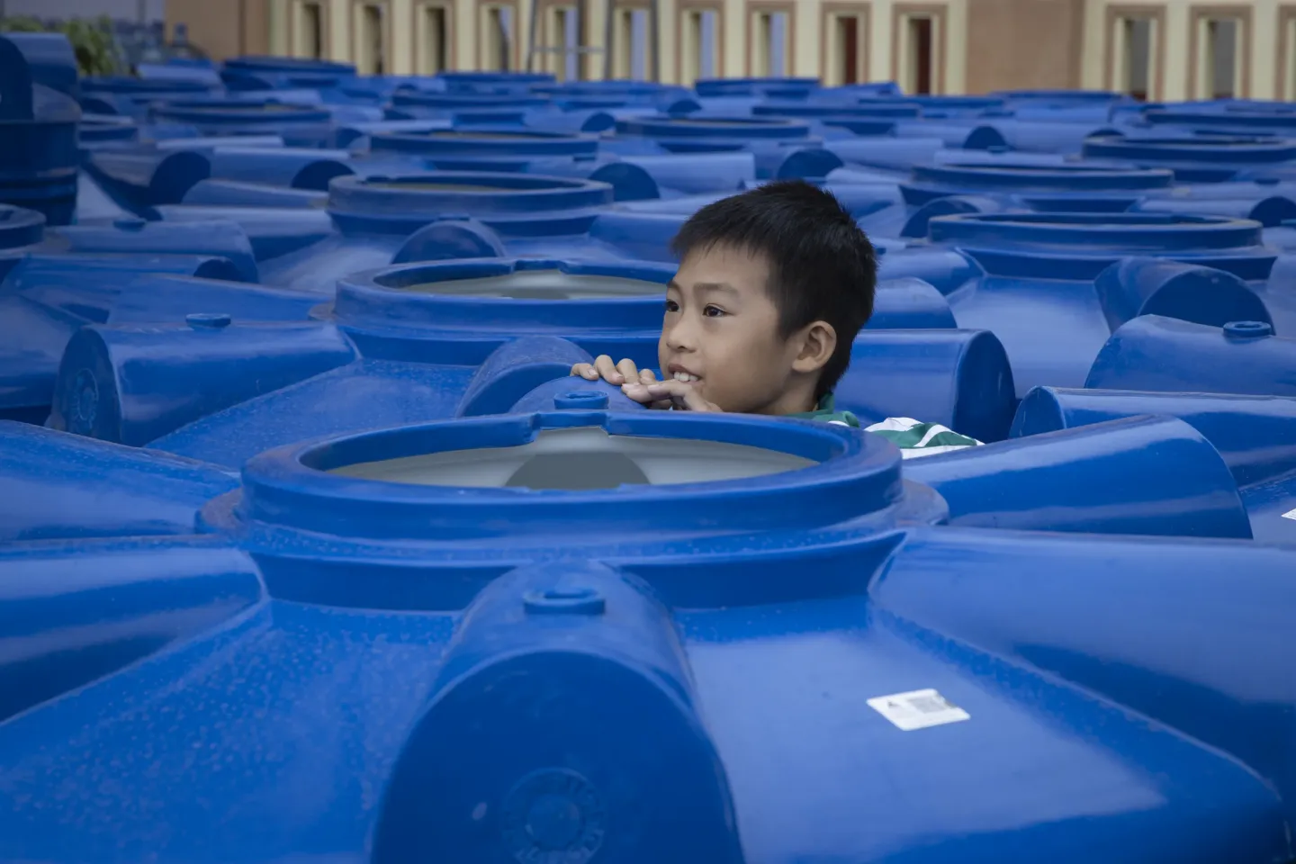 b&eacute; trai chơi giữa c&aacute;c b&igrave;nh chứa nước cứu trợ