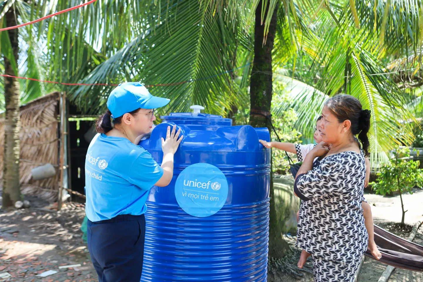 7 October 2026, Biển Bạch Commune, C&agrave; Mau Province, Viet Nam &ndash; Nguyễn Hồng Hạnh, Water, Sanitation and Hygiene (WASH) Officer at UNICEF Viet Nam, talks with Danh Thị Mai, who holds her youngest grandchild, beside a UNICEF-supported water storage tank with a capacity of 1,000 litres at her home.