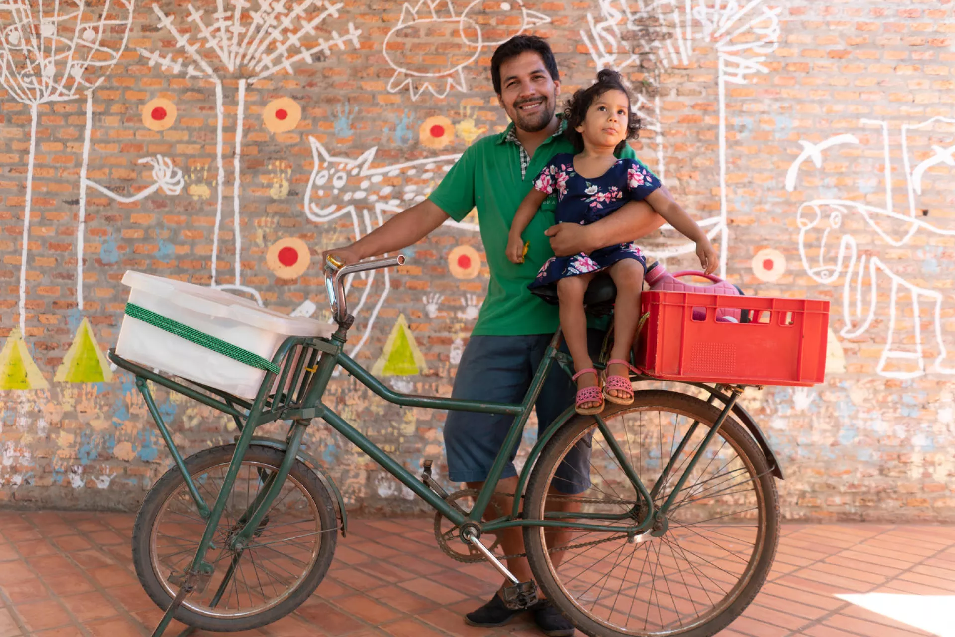 Rafael Alfonso Araujo, 27, holds his daughter Selva, 2, atop the bicycle that serves as the family's transportation and mobile food-sales cart at the Torore center in Aregu&aacute;, Central department, Paraguay,