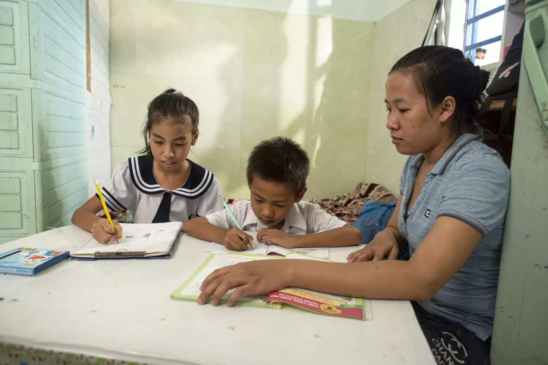 Mother helps two children - a girl and a boy study.