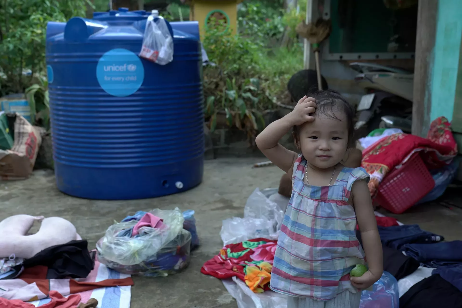 Ng&ocirc; Kh&aacute;nh Ng&acirc;n, 18 th&aacute;ng tuổi, đứng trước b&igrave;nh chứa nước hỗ trợ bởi UNICEF