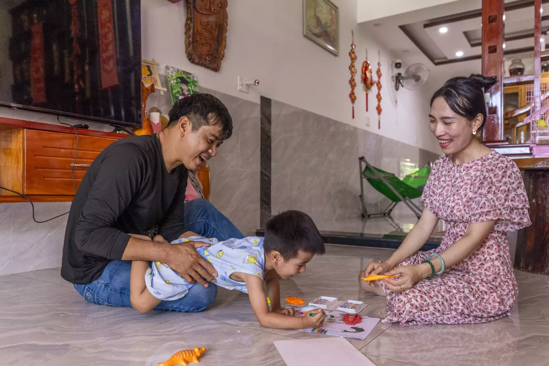 Vũ Khắc Tiến, 44 and Trần Thị Tuyết Loan, 36 play with their son Vũ Trần Anh Tuấn, 2 years old.