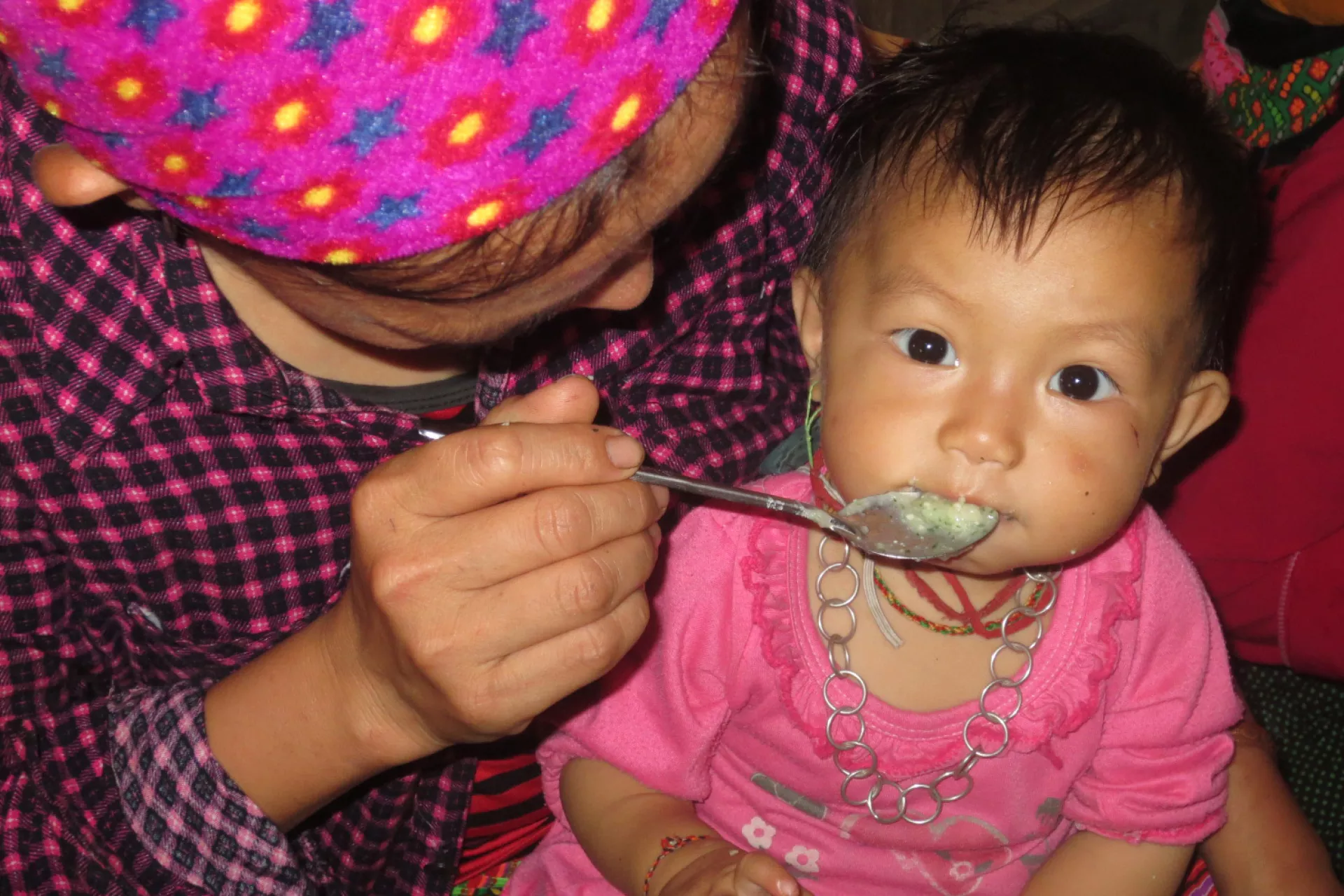A H'mong infant is fed nutrient-rich porridge, prepared at the child feeding and care club in Lao Cai