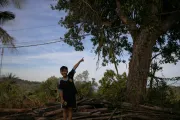 10-year-old Khoi, standing next to his childhood tree, outside his home.